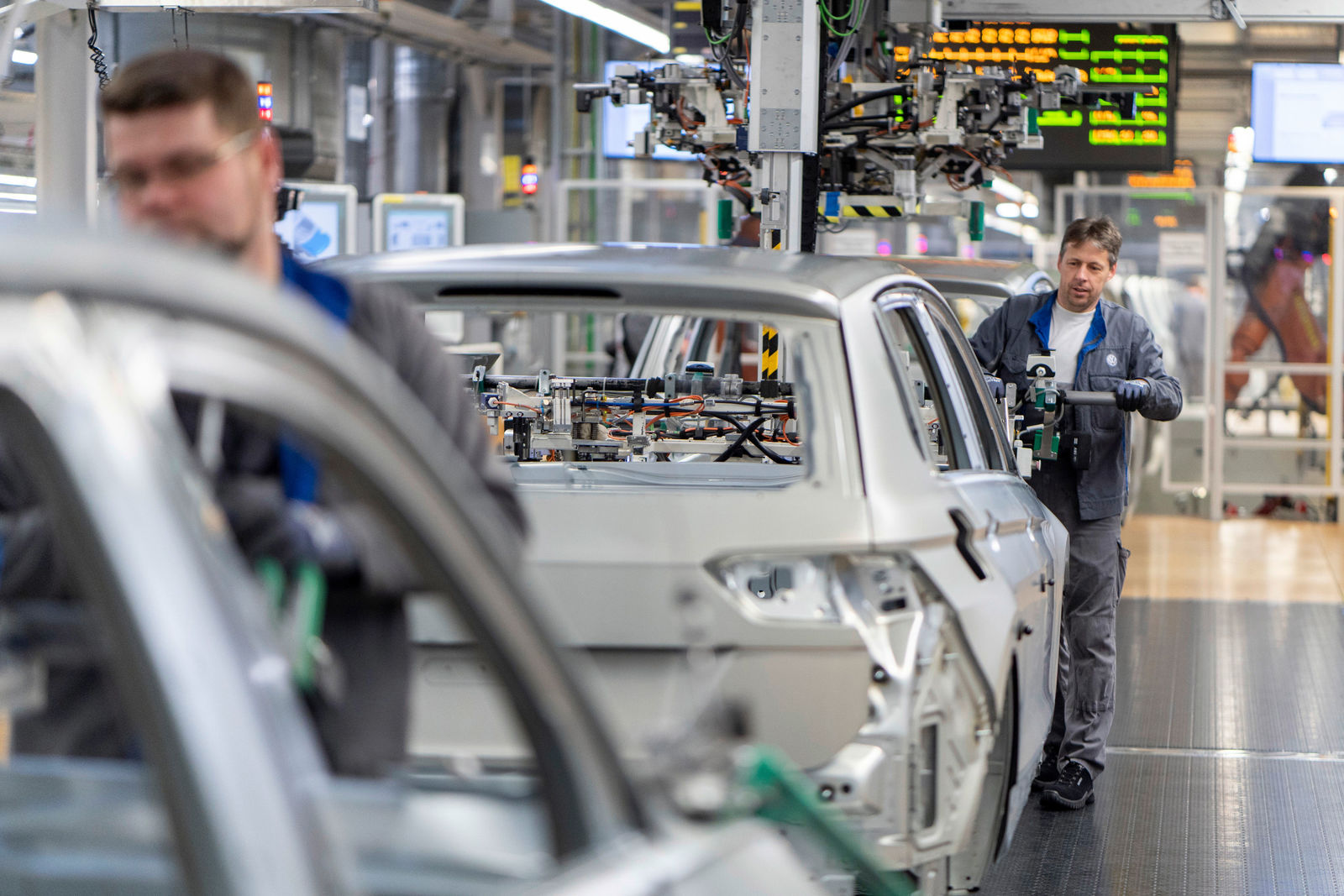 Karosseriebau Werk Wolfsburg: Ein Mitarbeiter montiert die Motorhaube eines Tiguan